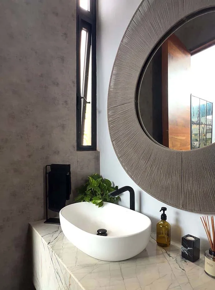 Baño con espejo circular y lavabo de mármol